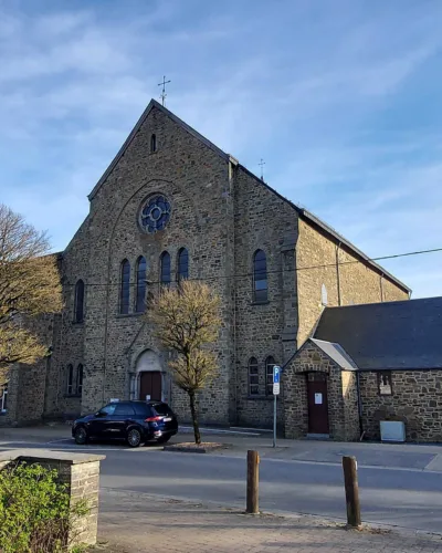 Église Saint-François à Bastogne vue depuis la rue avec sa façade en pierre et la place environnante